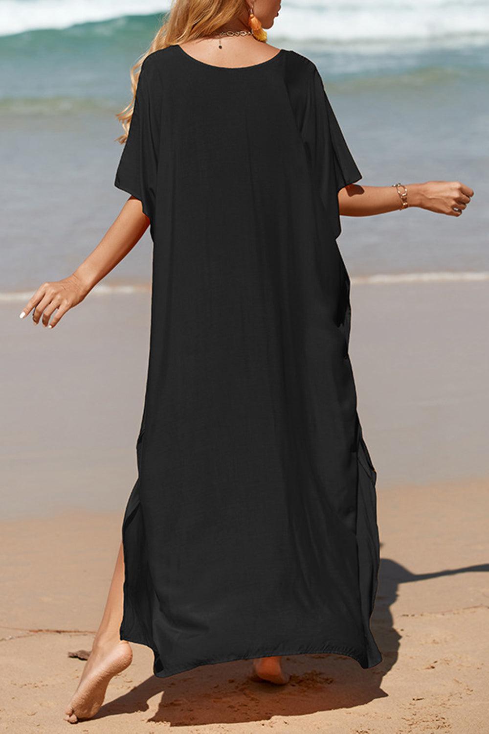 a woman in a black dress walking on the beach