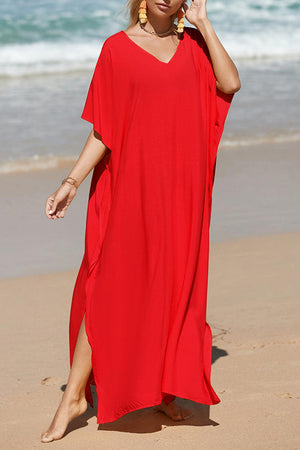 a woman in a red dress walking on the beach