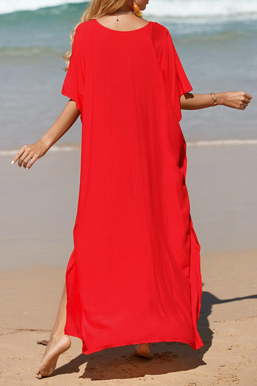 a woman in a red dress walking on the beach