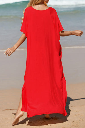 a woman in a red dress walking on the beach