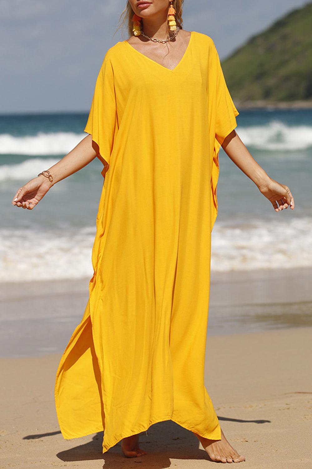 a woman in a yellow dress standing on a beach