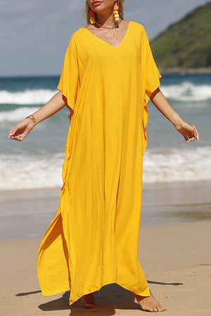 a woman in a yellow dress standing on a beach