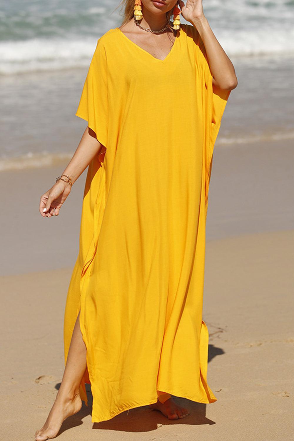 a woman in a yellow dress walking on the beach