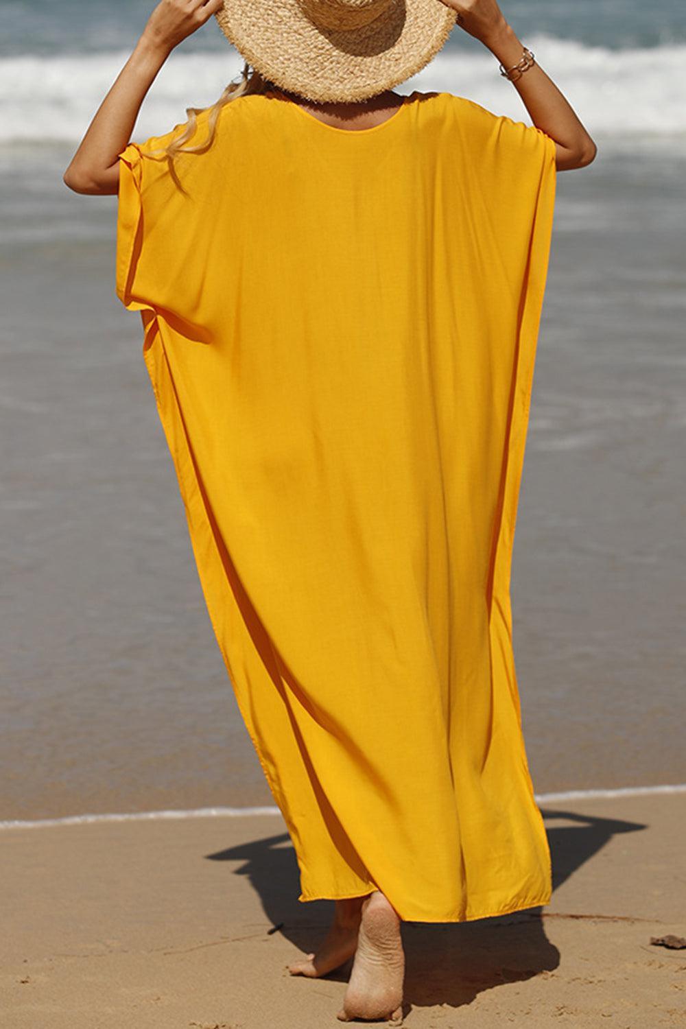 a woman in a yellow dress and a hat on the beach