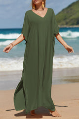 a woman standing on a beach wearing a green dress