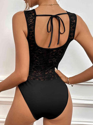 a woman wearing a black bodysuit with a lace back