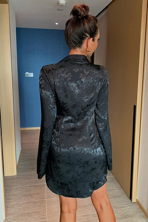 a woman in a black dress standing in a hallway