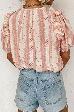 a woman wearing a pink and white blouse and denim shorts