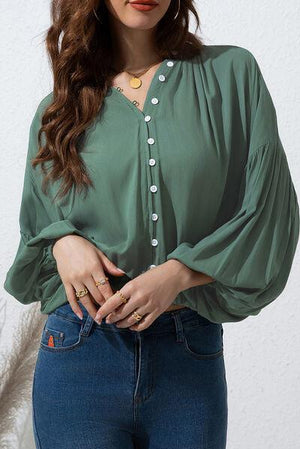 a woman wearing a green blouse and jeans
