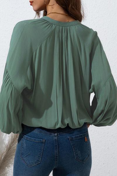 a woman wearing a green blouse and jeans