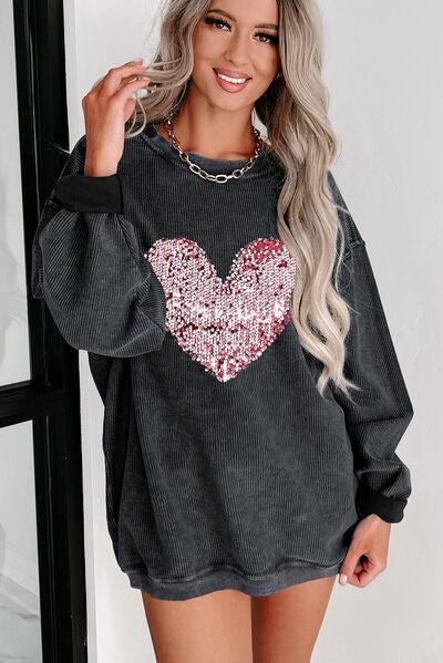 a woman wearing a black sweater with a heart on it