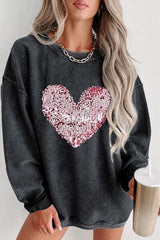 a woman wearing a black sweater with a heart on it