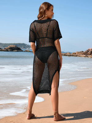 a woman standing on a beach wearing a black dress