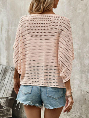 a woman wearing a pink crochet sweater and denim shorts