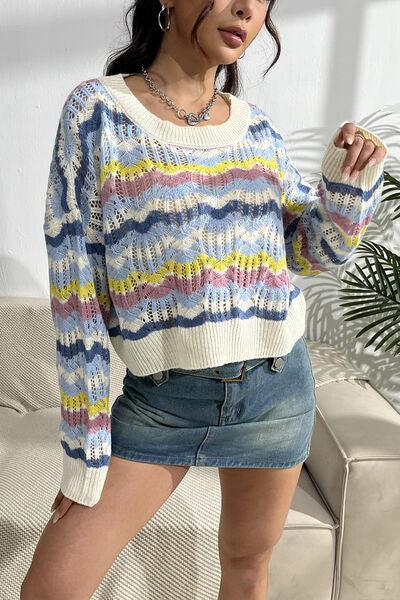 a woman standing on a couch wearing a colorful sweater