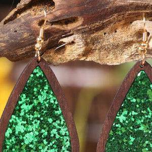 a pair of wooden earrings with green glitter