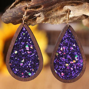 a pair of wooden earrings with purple glitter