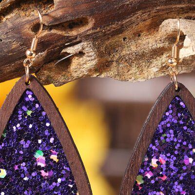 a pair of wooden earrings with purple glitter