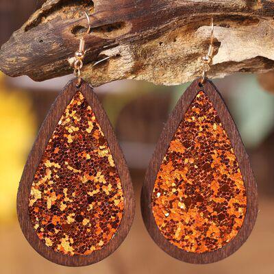 a pair of wooden earrings with orange and gold glitter