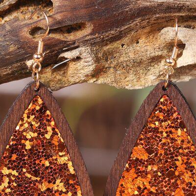 a pair of wooden earrings with gold glitter