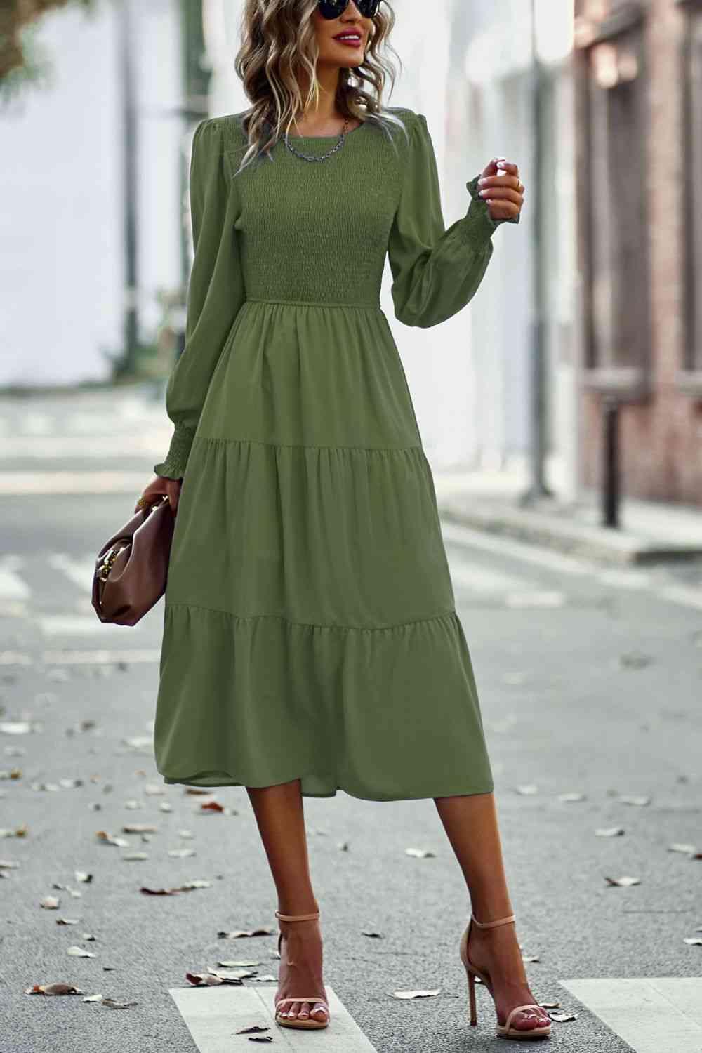 a woman in a green dress is standing on the street