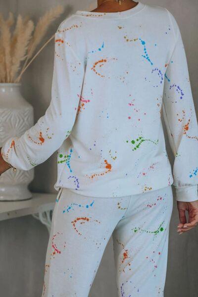 a woman wearing a white pajama set with colorful paint splatters