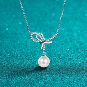 a necklace with a bow and a pearl