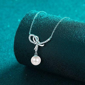 a necklace with a pearl and a bow on it