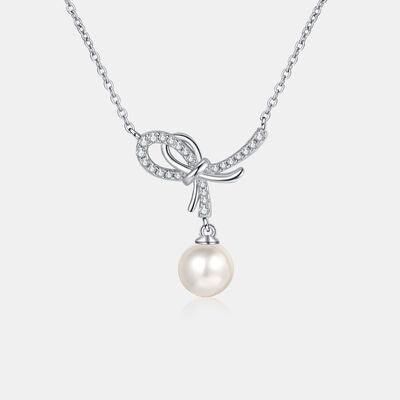 a necklace with a bow and a pearl