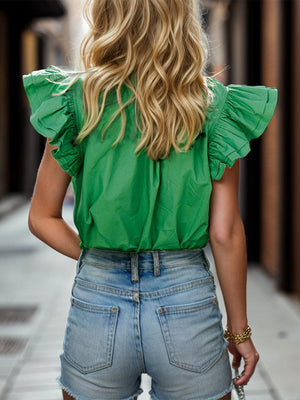 a woman wearing a green top and denim shorts