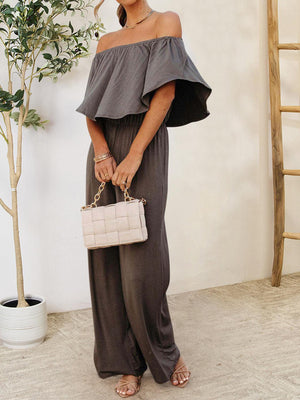 a woman in a grey jumpsuit holding a white purse