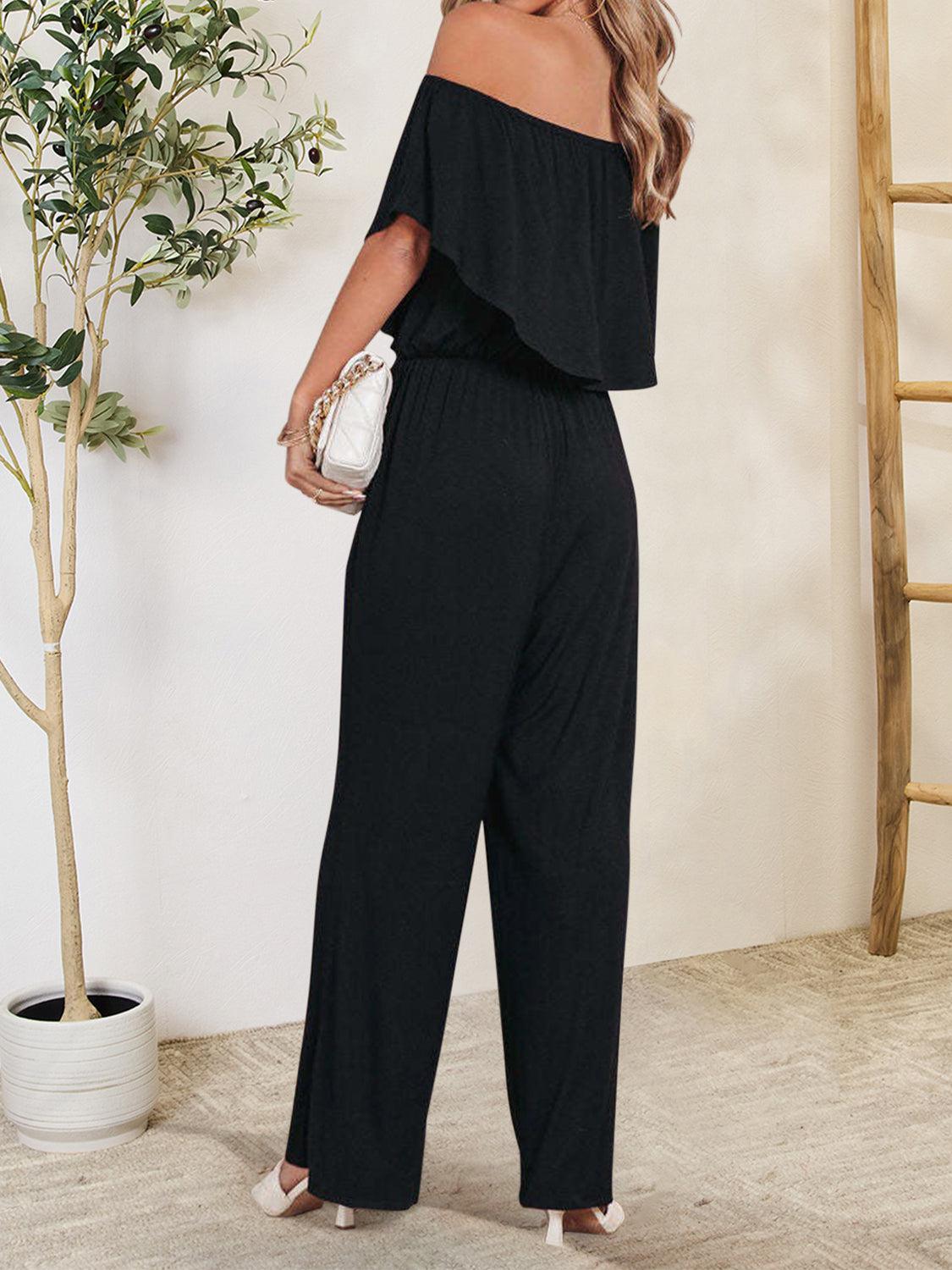 a woman wearing a black jumpsuit and a white purse