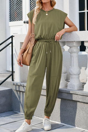 a woman wearing a green jumpsuit and white sneakers