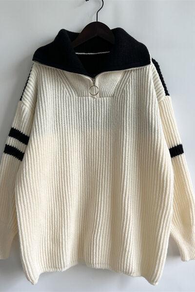 a white and black sweater hanging on a hanger