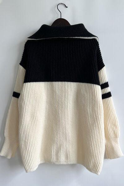 a white and black sweater hanging on a hanger