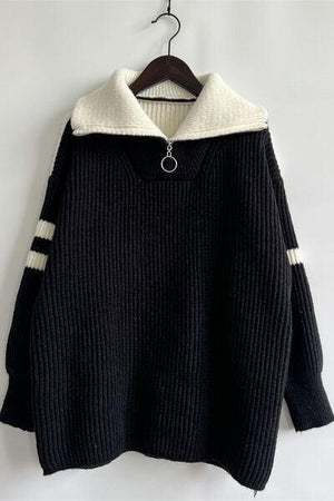 a black and white sweater hanging on a hanger