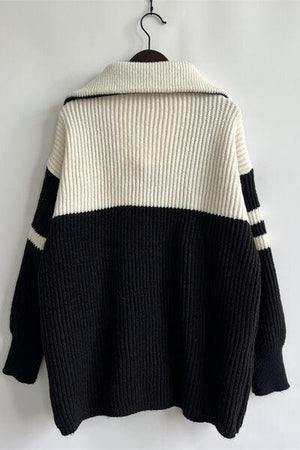 a black and white sweater hanging on a hanger