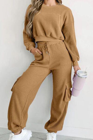 a woman wearing a brown sweater and pants