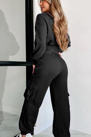 a woman wearing a black jumpsuit and sneakers
