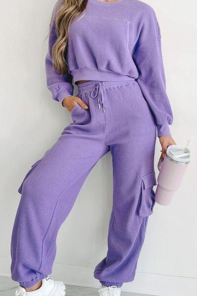 a woman wearing a purple sweater and pants