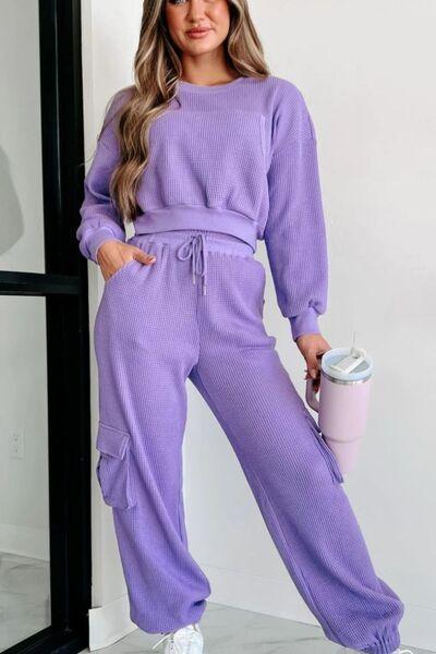 a woman wearing a purple sweater and pants