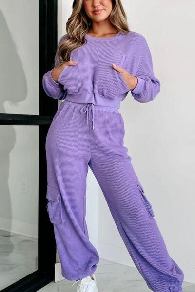 a woman wearing a purple sweater and pants