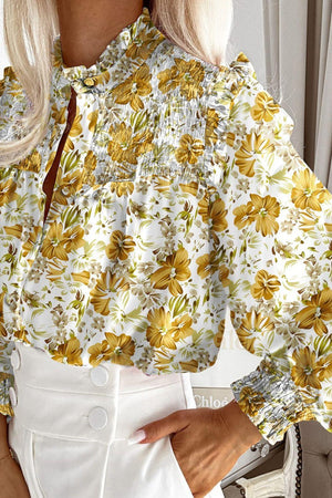 a woman wearing a floral blouse and white shorts