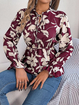 a woman sitting on a bed wearing a floral shirt