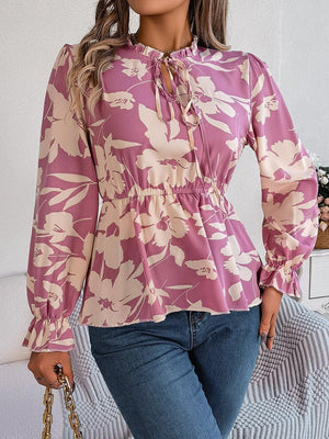 a woman wearing a pink floral blouse and jeans