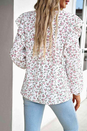 a woman wearing a white floral blouse and jeans