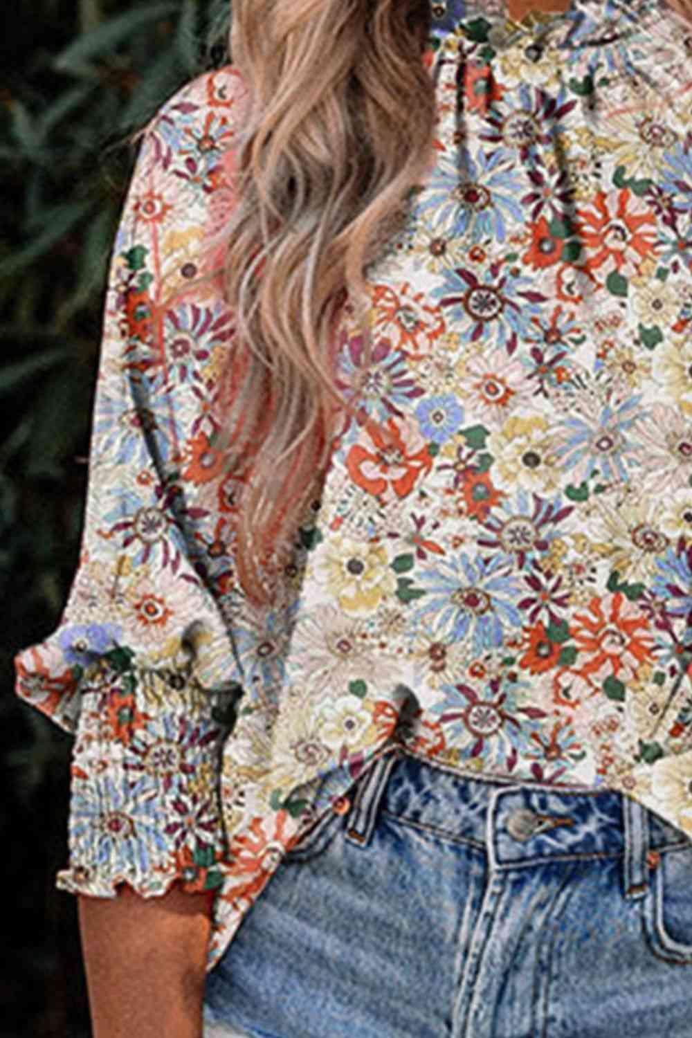 a woman wearing a floral blouse and denim shorts