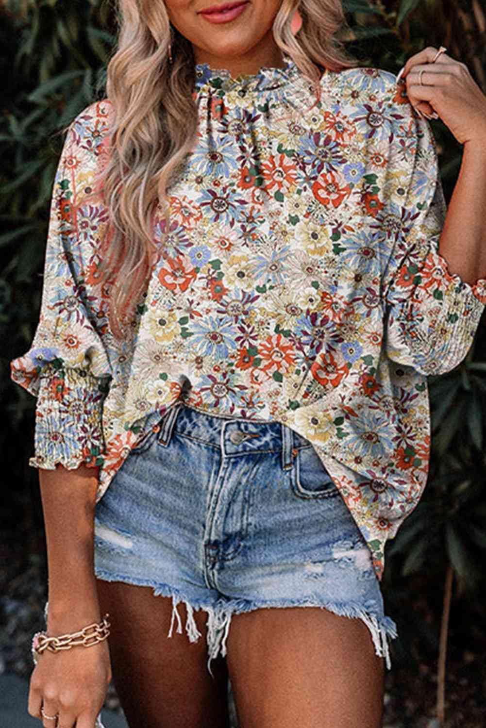 a woman wearing a floral blouse and denim shorts