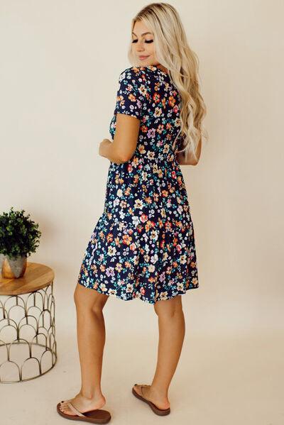 a woman in a floral dress standing in front of a white wall