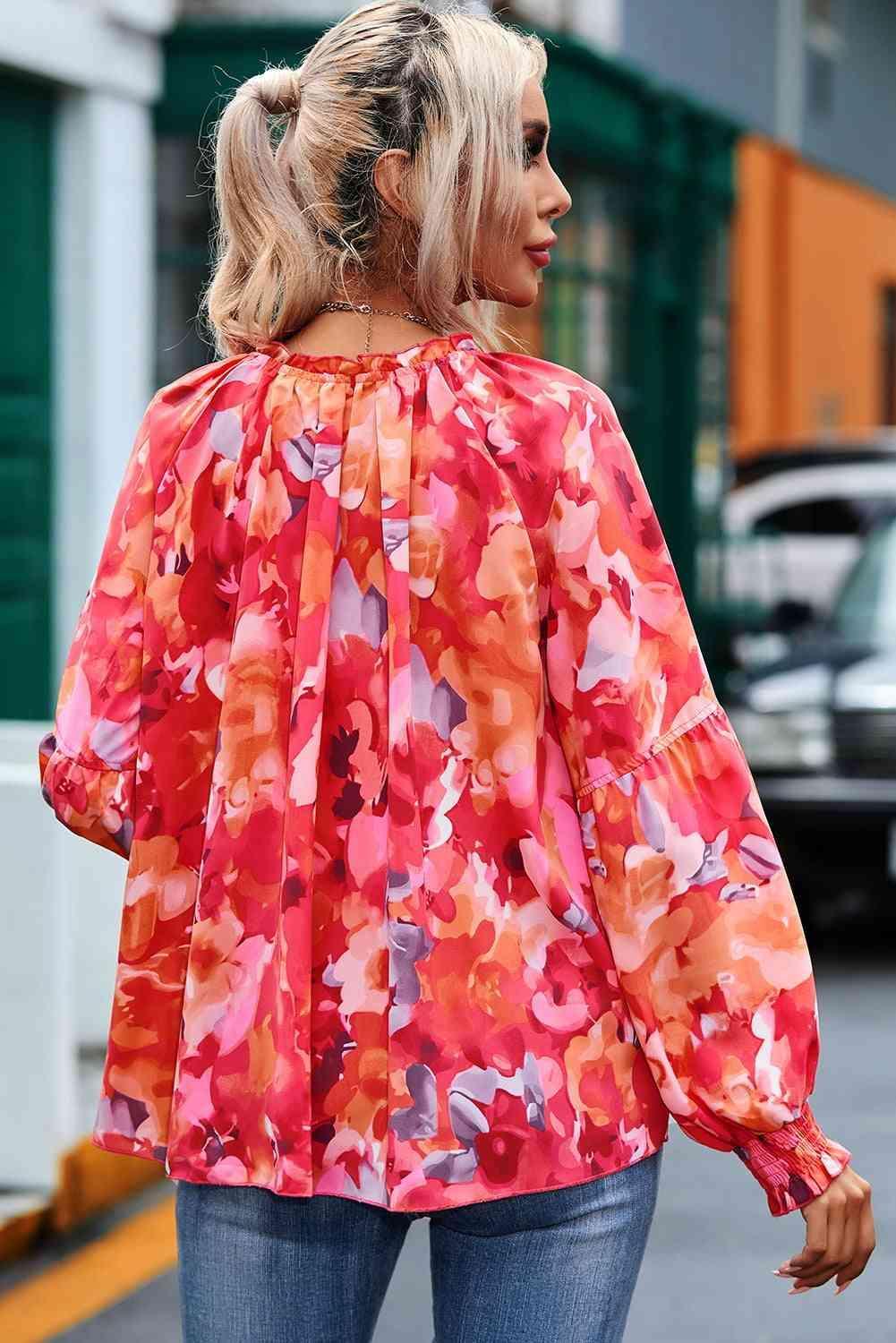 a woman walking down the street wearing a red floral blouse